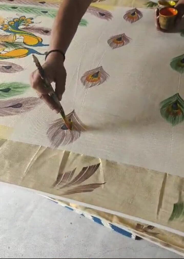Artist Painting intricate designs on a traditional saree with bright colors and delicate brush strokes.