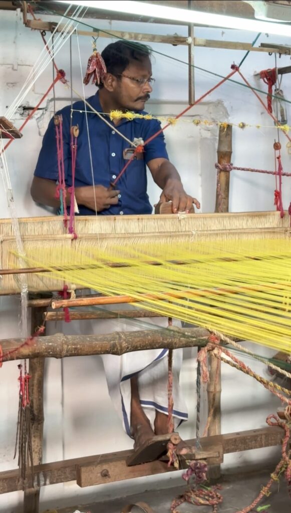 Male artisan weaving a traditional fabric on a handloom, showcasing the craftsmanship and skill of textile making.